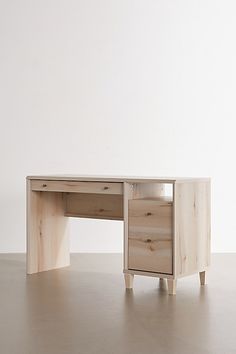 a wooden desk sitting on top of a hard wood floor next to a white wall