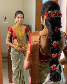 a woman in a red and gold sari is looking at herself in the mirror