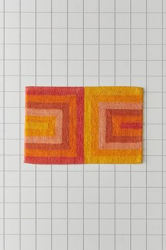 two orange and yellow rugs sitting on top of a white tiled floor next to each other