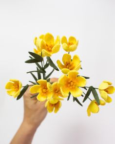 a person holding yellow flowers in their hand