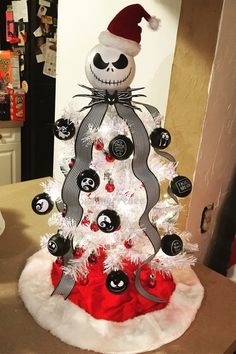 a white christmas tree with black and red ornaments on it's top, decorated in the shape of a jack - o - lantern