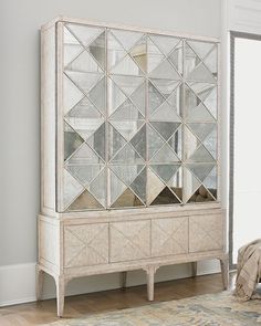 a living room with a couch, mirror cabinet and rug on the floor in front of it