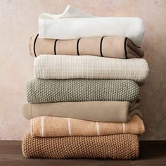 folded towels stacked on top of each other in different colors and patterns, against a beige background