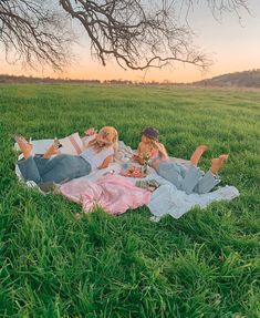 two women laying in the grass eating and drinking