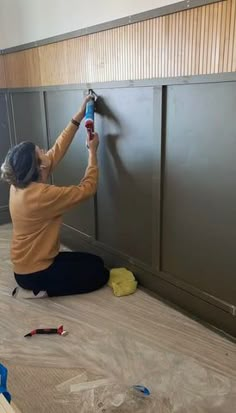 a woman is painting the walls in an empty room