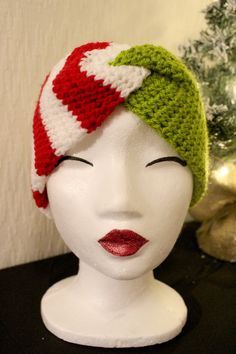 a white mannequin head wearing a green and red knitted hat