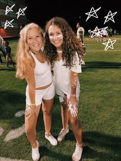 two young women standing next to each other on a field