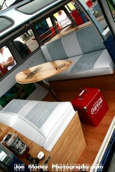 the inside of a boat with two couches and a surfboard