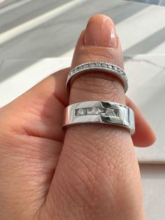 a woman's hand with two wedding bands on her finger and the ring has three diamonds in it