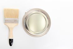 a paint brush next to a tin with a mirror on the top and another item in the bottom