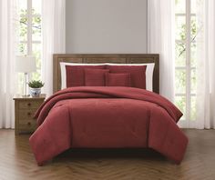 a bed with red comforter and pillows in a room