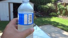 a hand holding a bottle of water in front of a house