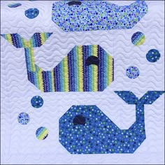 a quilted wall hanging with blue and green designs on it's sides, along with an image of a whale in the water