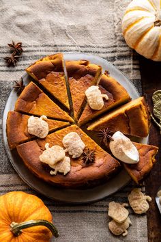 a pie with several slices cut out on a plate next to pumpkins and spices