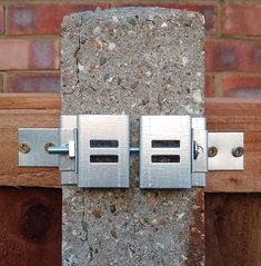 two metal latches are attached to the side of a brick wall with wood planks