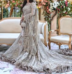 a woman in a wedding dress standing next to a couch with flowers on the wall