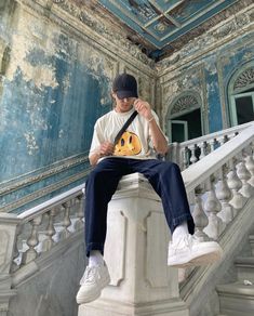 a man sitting on top of a white stair case next to a handrail holding a guitar