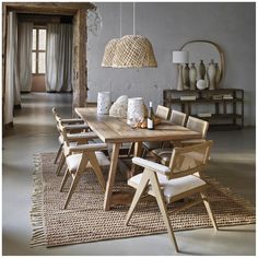 a dining room table with chairs and vases on the floor in front of it