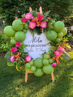 a sign that is on the grass with flowers and fruit around it in front of some trees