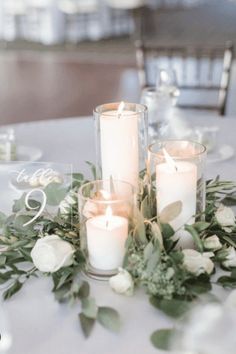 candles and greenery are arranged on the table