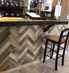 a bar with a counter top made out of wooden planks and black barstools