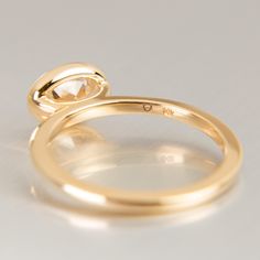 two gold wedding rings on a white surface with one ring facing the camera and the other looking down at it