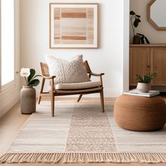 a living room with a chair, rug and potted plant on the floor in front of it