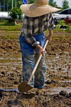 a man with a straw hat is shoveling in the mud