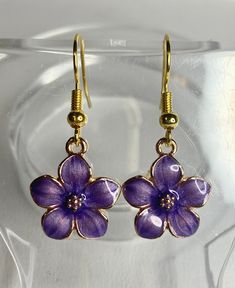 These little purple flowers are just the cutest things I've ever seen! They go great with just about anything, whether it's a pair of jeans or a date night to a movie. Made with gold plated metal and enamel, hanging from stainless steel ear wires.These measure 1.25" (Approximate measurement, includes ear wire)Any metals used in jewelry are Zinc alloy (lead and nickel free), tarnish resistant (except for copper, which will change color(patina) over time). Metals are either bare copper, silver-ton Trendy Gold Flower Charm Earrings, Trendy Gold Enamel Earrings, Trendy Nickel-free Enamel Earrings, Spring Flower Enamel Earrings, Trendy Enamel Nickel-free Earrings, Purple Flower Charm Earrings, Enamel Jewelry For Spring Gifts, Spring Purple Flower Earrings For Pierced Ears, Spring Enamel Jewelry For Gifts