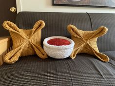 a crocheted bowl and two star shaped pillows on a couch with a painting in the background