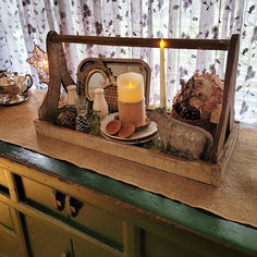 a candle is lit on top of a wooden tray with dishes and other items in it