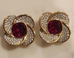 Vintage  Clip On Earrings with Beautiful  Ruby Red colored center crystal surrounded by shiny clear crystals. The center crystal looks darker on the photo. Gold Tone backing with strong clips.  Stunning earrings, perfect for any occasions.  Measures 1 inch x 1 inch size. Excellent vintage condition.   Swan marked on the back. Designer Costume Jewelry, Photo Gold, Vintage Clip On Earrings, Fall 24, Faux Pearl Earrings, Cameo Brooch, Topaz Earrings, Vintage Clip, Clear Crystals