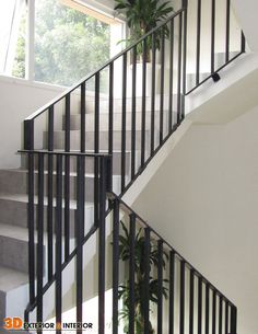 a staircase with black railings and a potted plant