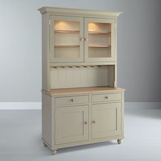 a white china cabinet with glass doors and drawers on the front, in an empty room