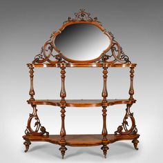 an ornate wooden shelf with a mirror on it's top and two shelves below