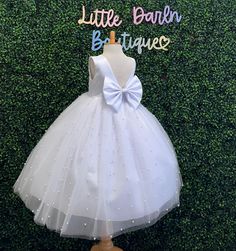 Our enchanting Ankle Length flower girl dresses are sure to turn heads! This beautiful elegant sophisticated dress is handmade, the bodice consists of White Bridal Satin with a sowed in sash at the waist, the back of the dress consists of an open V-back with a hidden zipper. The big bow is detachable. The skirt consists of 4 layers of tulle with the top layer consisting with sowed in pearl beads. The fifth layer is made of lining with crinoline for fullness.  This dress is perfect for any occasi Fitted Sleeveless Pageant Dress For First Communion, Fitted Sleeveless Ball Gown For First Communion, Fitted Princess Dress With Satin Bow For Baptism, First Communion Princess Dress With Satin Bow, Elegant Tutu Dress With Satin Bow For Weddings, Fitted Princess Dress With Satin Bow For First Communion, Elegant Tutu Wedding Dress With Satin Bow, Elegant Wedding Tutu Dress With Satin Bow, Elegant Spring Ball Gown For First Communion