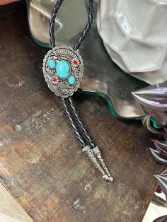 This awesome bolo tie has a southwestern design and faux turquoise pieces. The cord is genuine leather.   Measurements/Sizing   Total length of leather is approx. 40 inches 2 3/8 x 2 7/8 in pendant Bohemian Hand Tooled Jewelry For Rodeo, Concho Jewelry For Rodeo, Southwestern Lariat Bolo Tie For Rodeo, Southwestern Style Adjustable Bolo Ties, Adjustable Concho Jewelry For Rodeo, Bohemian Concho Bolo Ties For Rodeo, Concho Lariat Bolo Tie For Western-themed Events, Bohemian Concho Jewelry For Rodeo, Concho Bolo Ties For Western-themed Events