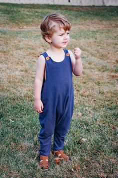 a little boy standing in the grass with his fist up