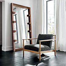 a black chair sitting in front of a mirror on top of a hard wood floor