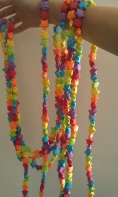 a person holding up a multi - colored beaded necklace