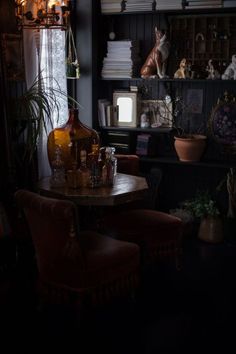 a table with two chairs and a bottle on it in front of a bookshelf