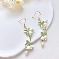 🍀 Size: 7.3x1.4 cm 🍀 Material: Freshwater Pearl, 14K Gold Plated Sterling Silver Hook, Brass (✨Hypoallergenic Hook✨) Description 🌸 Add a touch of delicate elegance to your look with these extremely intricate and delicate Lily of the Valley earrings. These ethereal dangle earrings feature freshwater pearls and the iconic bell-shaped blooms of the Lily of the Valley flower, creating a romantic and sophisticated look. Each flower is flexibly attached to the stem, creating a lifelike vivid look.  These earrings are perfect for brides-to-be or as a special gift for your bridesmaids. They also make for a great addition to any formal or special occasion outfit. Please note that freshwater pearls are naturally unique and may exhibit slight variations in size, shape, and colour. 🌸 ⭐️ Shop more Green Flower Shaped Jewelry For Wedding, Green Flower-shaped Wedding Jewelry, Green Flower Shaped Wedding Jewelry, Flower Shaped Single Earring For Wedding, Single Flower-shaped Earring For Weddings, Elegant Green Hoop Earrings For Wedding, Wedding Jewelry Single Flower Shaped Earring, Pierced Flower Wedding Earrings, Flower Shaped Wedding Earrings