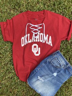 "OU grommet line v-neck tee with white knit ties will be great to wear to the up coming football games.  You can choose original hem, crop (20\" from back neck to hem) or crop top with front ties.    100% cotton PLEASE NOTE:  the second picture is  the new tee that is available.  That will be the one I will be using this season. In addition to the crimson color tee ( in the pictures) other colors available are white and black. Please let me know.  If you would like a lace inset instead of the grommet lined v-neck, message me.  6 1/2 depth of v-neck Wash wash, inside out, line dry flat" University Of Oklahoma Game Day Outfits, Neck Message, Crimson Color, Original Hem, College Tees, Game Day Outfit, University Of Oklahoma, Knit Tie, Football Outfits