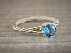 a close up of a ring with a blue stone in it on a wooden surface