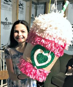 a woman standing next to a giant cupcake with pink and green decorations on it