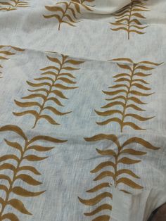 a white and gold fabric with leaves on it