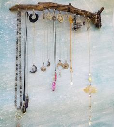 several necklaces hanging from a tree branch on the snow covered ground with beads and charms attached to it