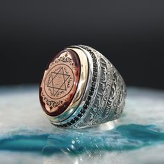 a silver and gold ring sitting on top of a blue plate with a pentagramil