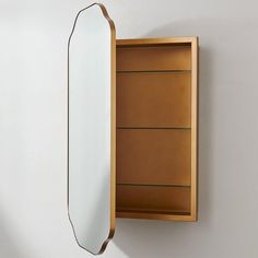 a mirror mounted to the side of a wall next to a wooden cabinet with drawers