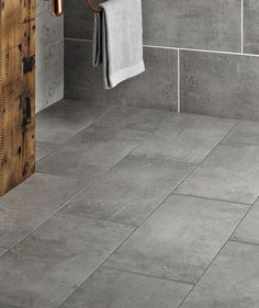 a bathroom with grey tile and wooden door, towel rack and toilet paper dispenser